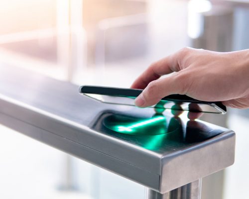 Using smartphone to open automatic gate machine Male hand using smartphone to open automatic gate machine in office building